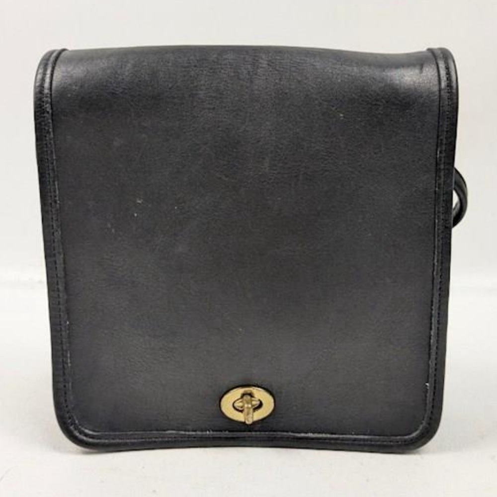 Vintage coach leather crossbody with the flap and gold buckle .